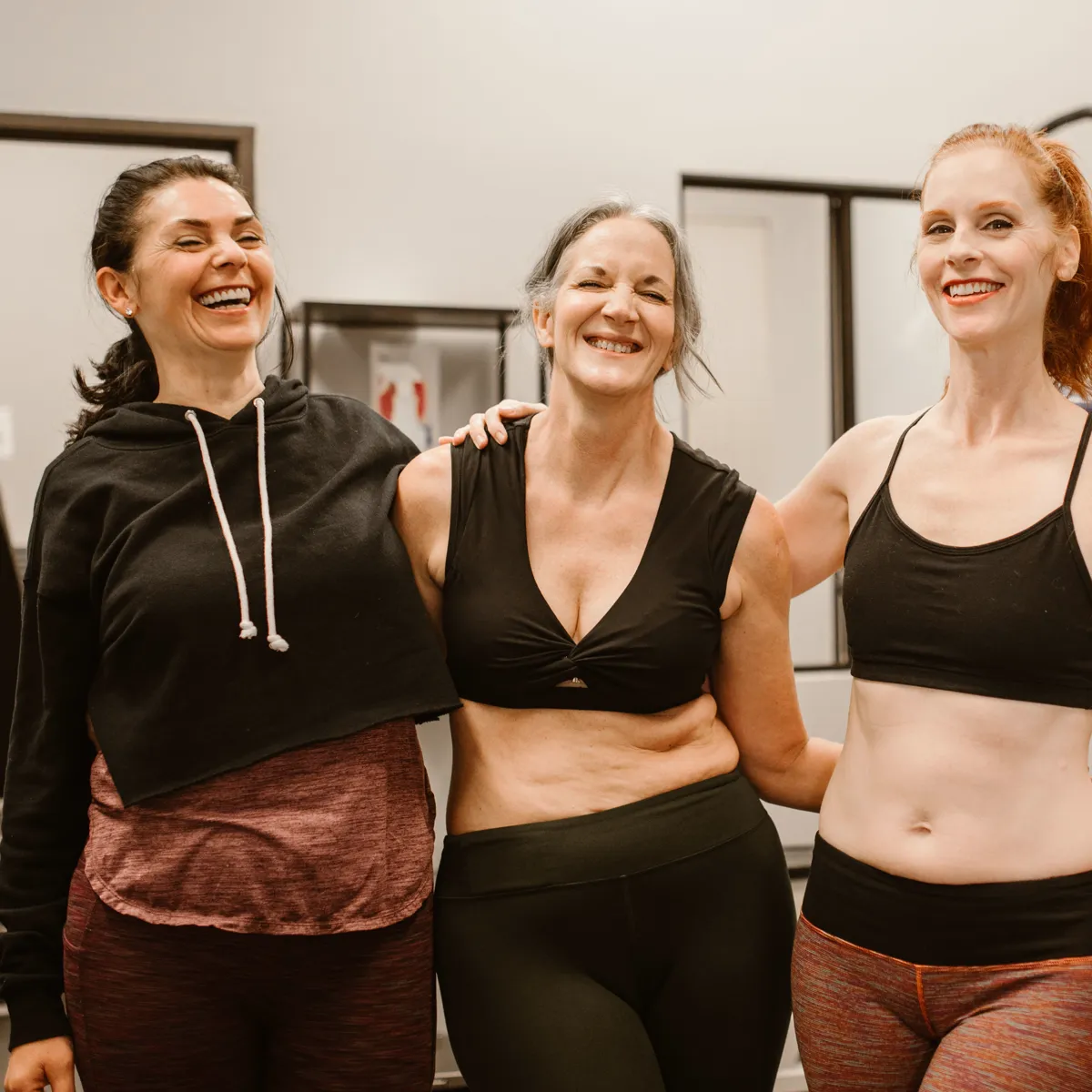 Three smiling women together at the gym after a strength workout